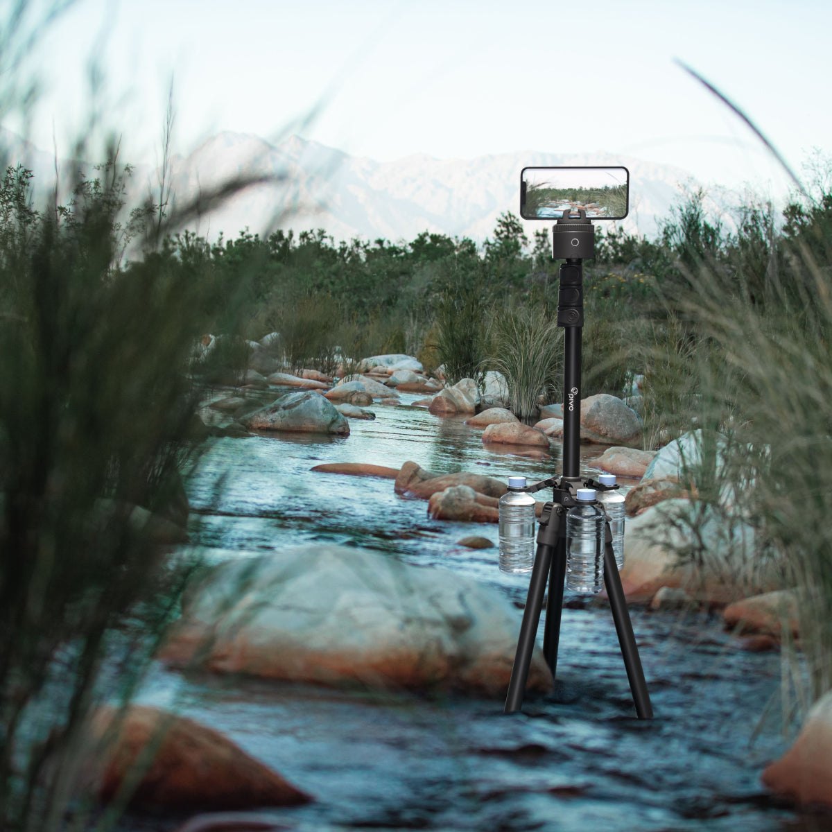 Eco-friendly tripod weight with adjustable water bottles attached to stabilize a tripod by a river outdoors